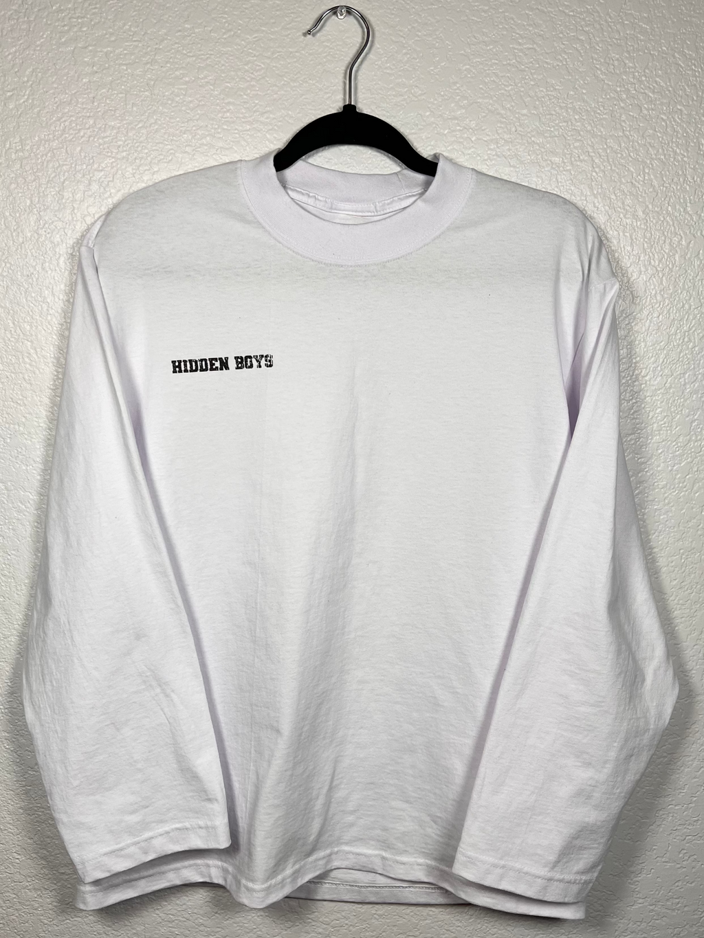 White long-sleeve shirt with text on a hanger against a plain background